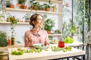 Young woman sitting with healthy food in the beautiful interior with green flowers on the background
